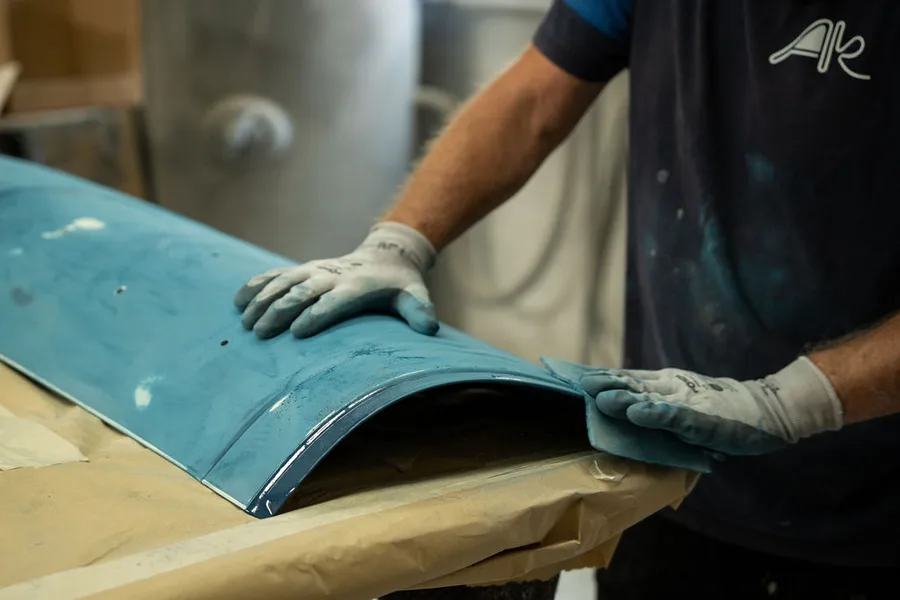 Medewerker werkt met de hand een gespoten paneel na